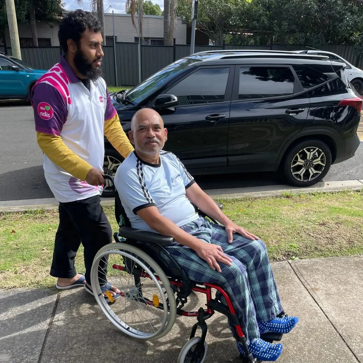 Support worker with a participant beside the car before an outing